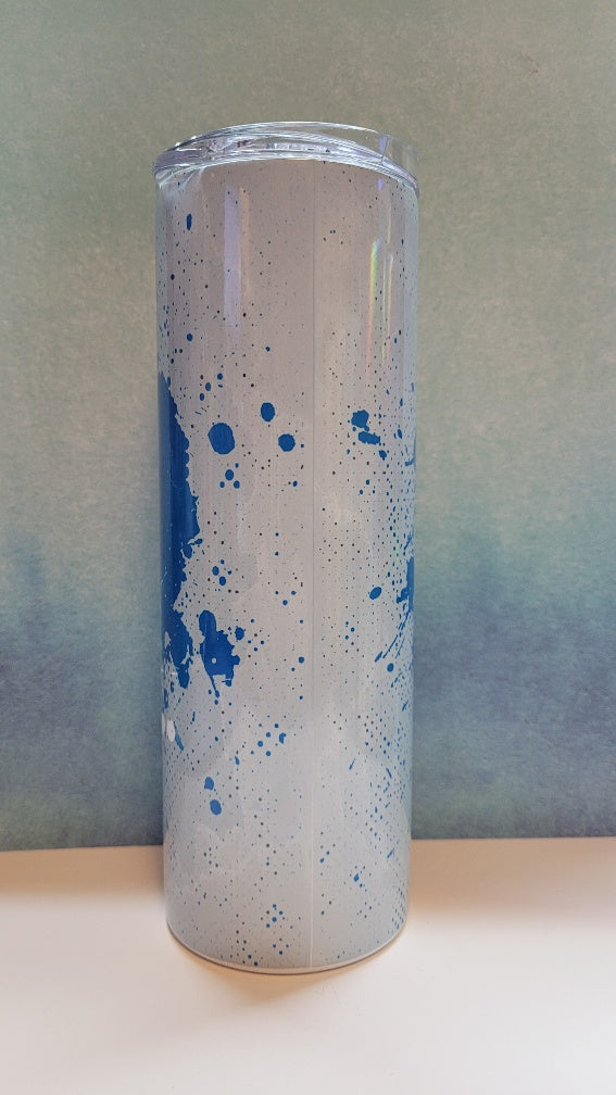 Tall cylindrical glass with blue speckles on a neutral background