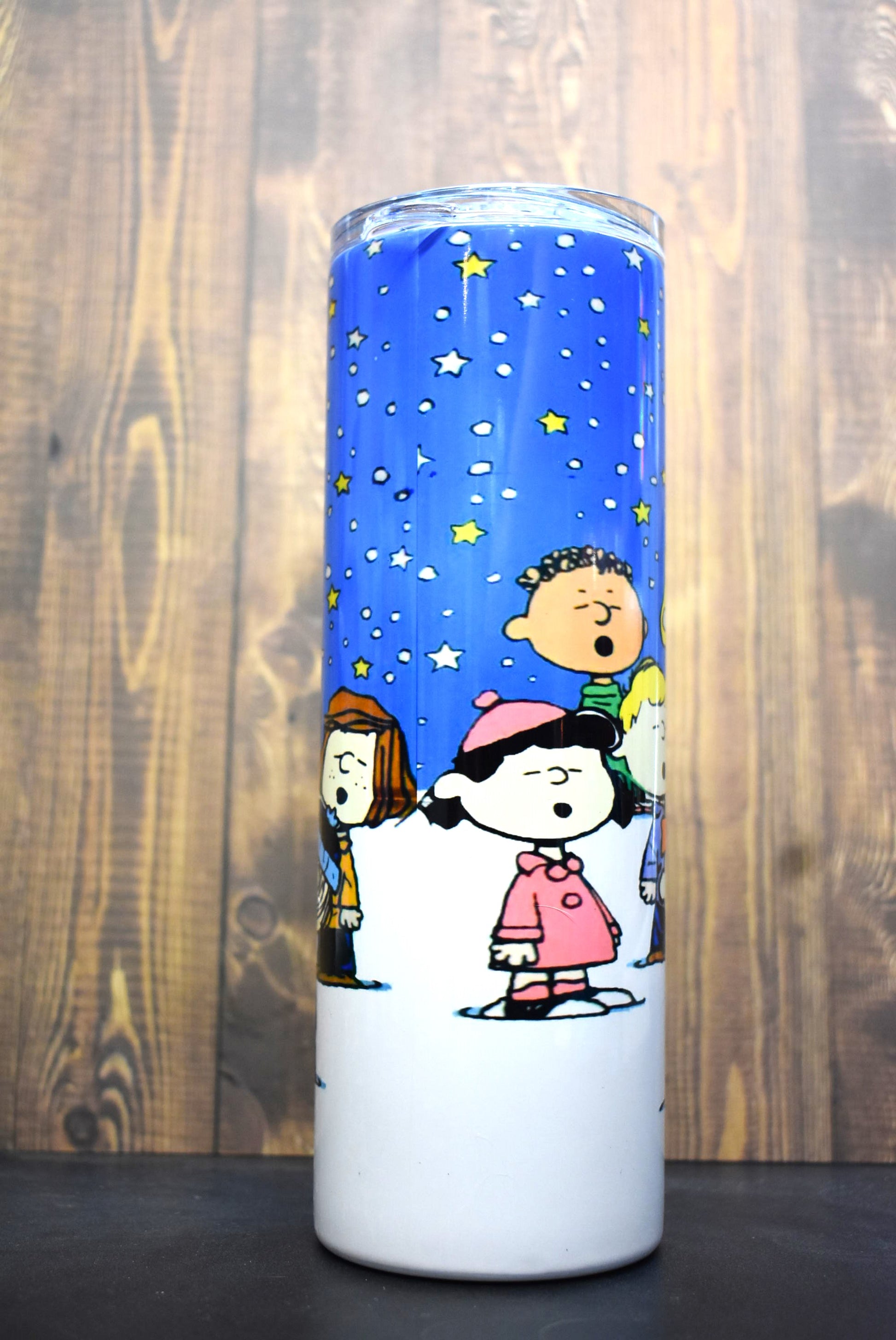 It's a Peanuts Christmas. The whole gang from Charlie Brown, Snoopy, Woodstock and more stand outside under the stars singing Christmas carols by the tree, 