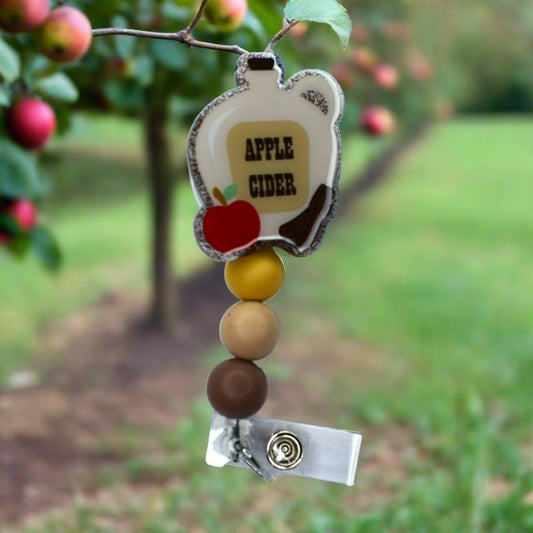 This acrylic badge reel sports a traditional-style jug of apple cider, with 3 silicone beads of various tan hues.