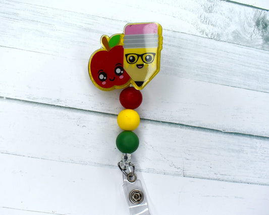 This acrylic badge reel, featuring an adorable smiling apple and pencil with a vibrant combination of red, green and yellow silicone beads.