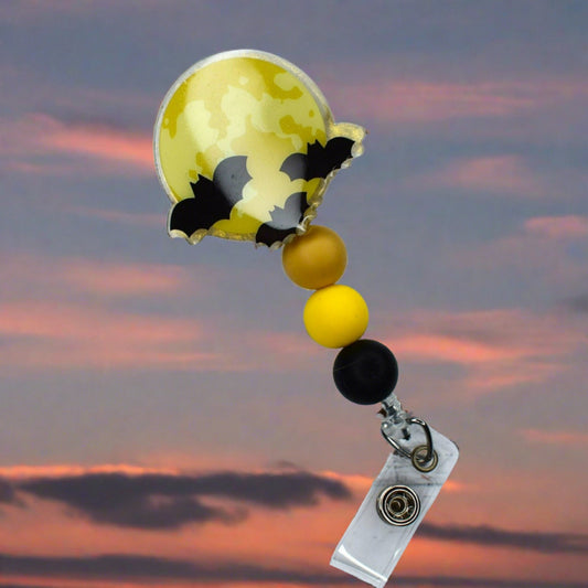 This acrylic badge reel is an ideal accessory for Halloween, featuring a full moon base with 3 bats in the air, completed by yellow, tan, and black silicone beads.