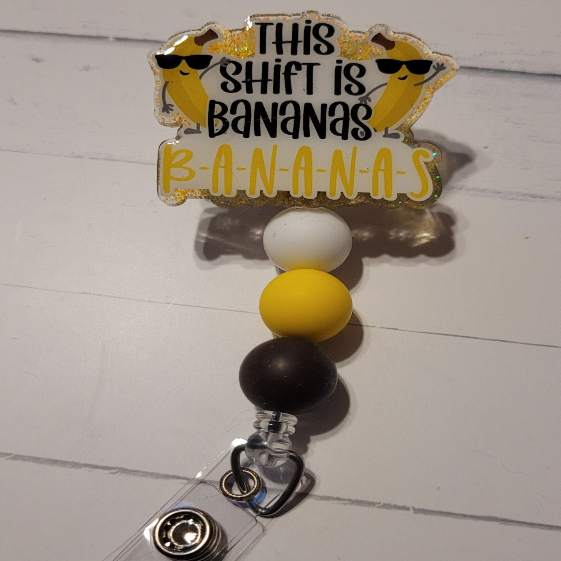 ananas....Yes that crazy shift that is absolutely Bananas. We bring you yet another new addition to our Medical Series Badge Reels. This Shift Is Bananas. 2 cool bananas wearing sunglasses on the front with yellow glitter on the back with color coordinating silicone beads to finish the craziness. Plays well with our Night Shift Era Badge Reel.