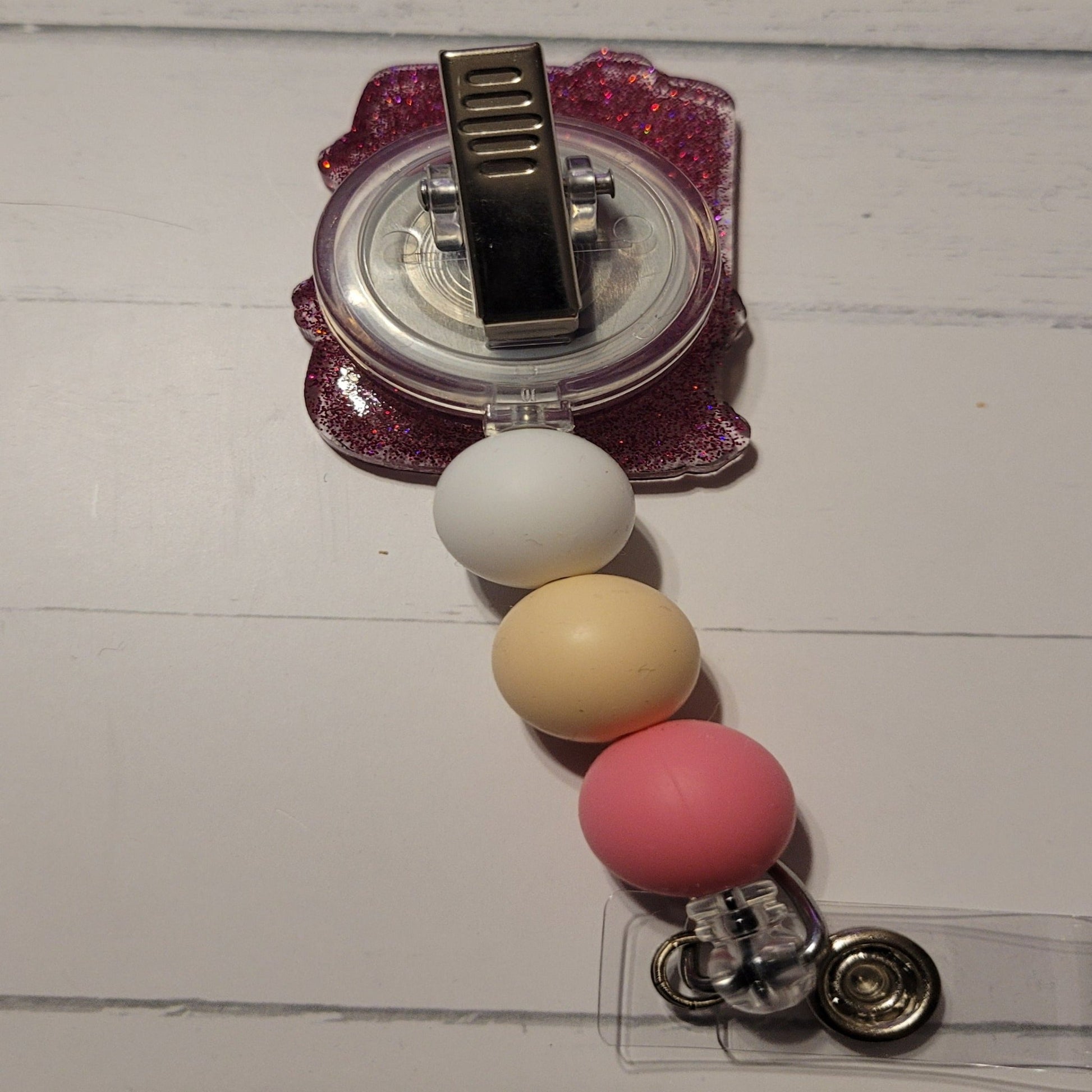 Know a librarian or a book worm that can use a Badge Reel. Here we have our Bookish Passport. Books open the door to your imagination to go or be anyone without having to actually get a real passport. A pink theme here with an open book on the front, purplish pink glitter back, and 3 color coordinated silicone beads to finish the look.