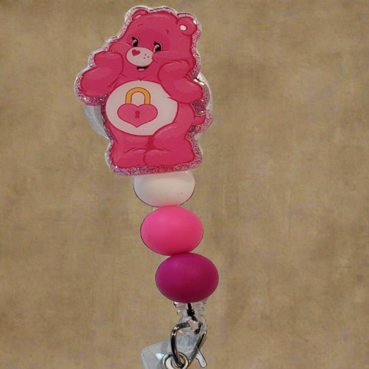 Looking for a charming badge reel? Well, look no further because we've got our Secret  Bear here! With a glittery pink back and 3 matching silicone beads, it's perfect for all the bear lovers out there. This is 1 of 5 variations.