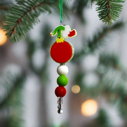 Be aware, as a burglar is about to perform a heist on the festive red ornament depicted on this badge reel. The green glitter background and small red, green, and white silicone accent beads complement this Grinchy design perfectly.