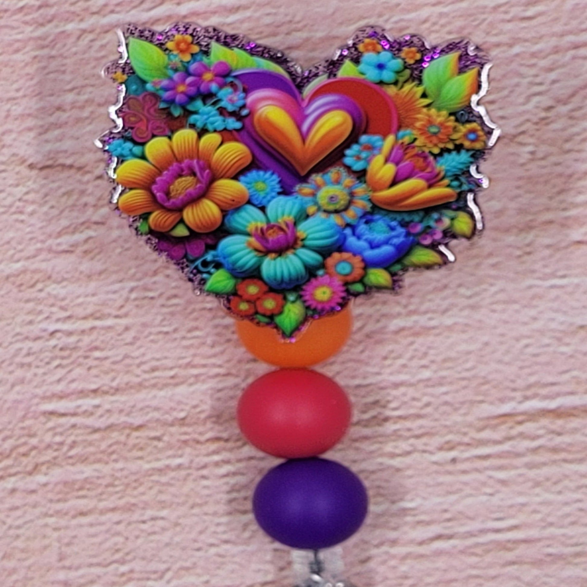 This Badge Reel utilizes an attractive floral pattern in a bold color palette. The design is complemented by a purple glitter base and three coordinated silicone beads.