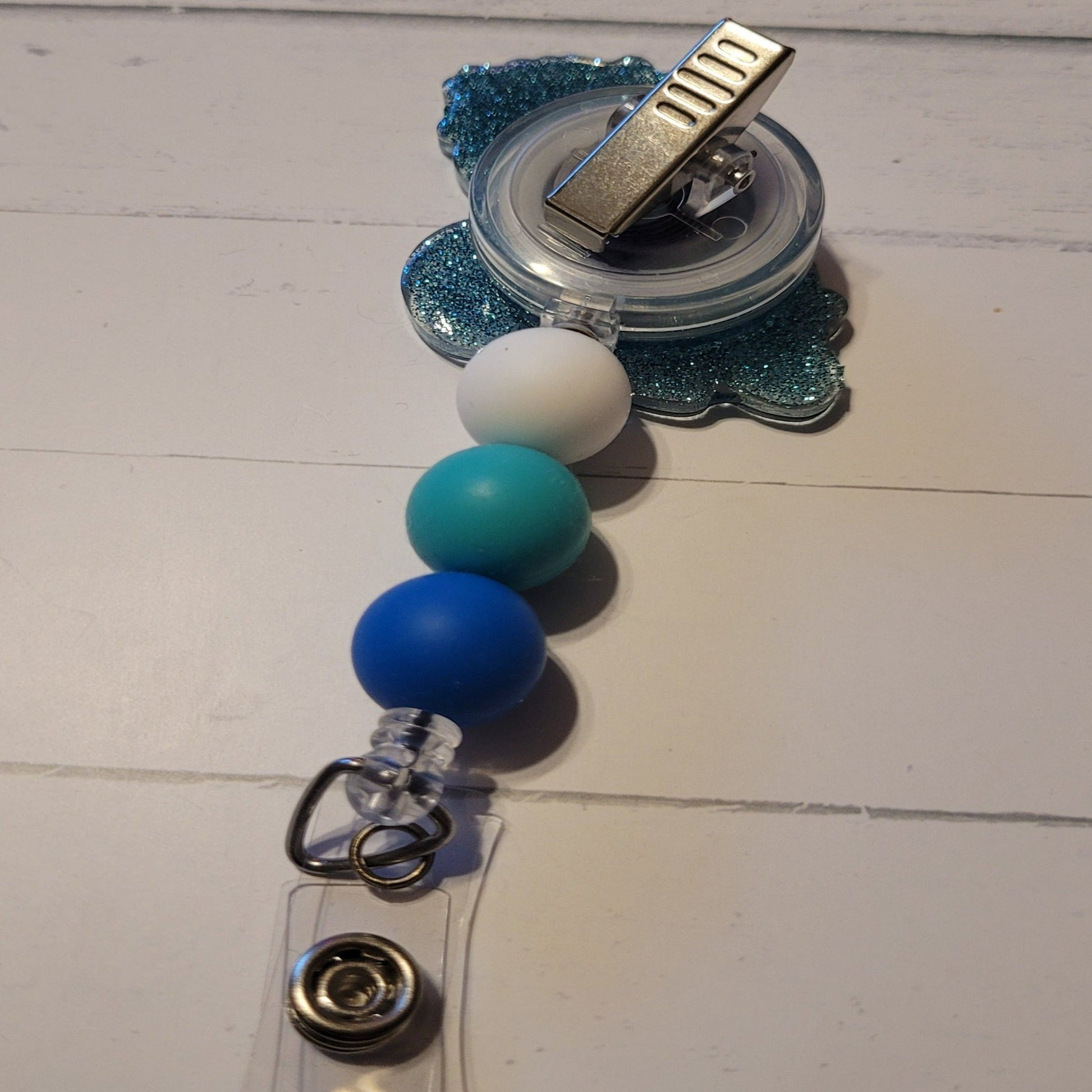 How cute is this happy little blue turtle with a floral head band! A beautiful bouquet sits on his head with a smile on his face. Features a blue glitter back and an adorable trio of matching silicone beads for a dash of extra charm. Perfect for all animal enthusiasts!