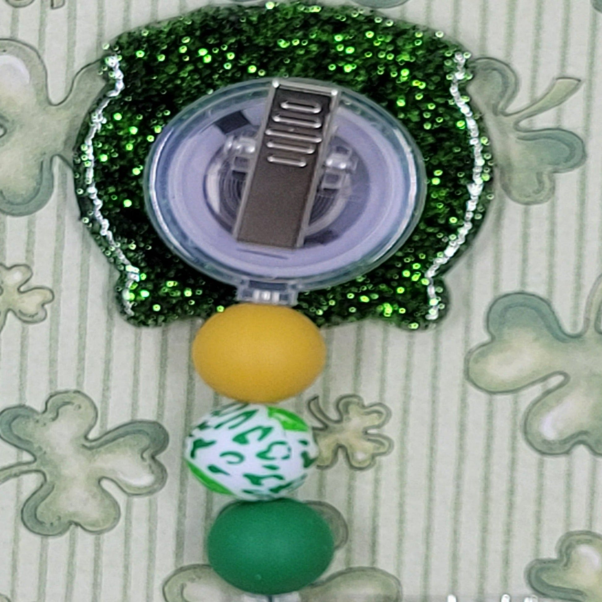 Celebrate St. Patrick's Day with our Happy Pot Of Gold badge reel. This charming pot is filled with gold and features a dark green glitter base and 3 coordinating silicone beads for a festive, professional look.