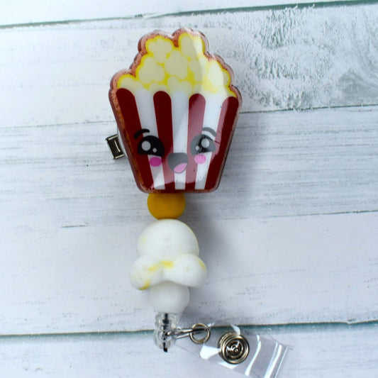This Badge Reel includes an acrylic box of popcorn bearing a cheerful face and a popcorn-shaped focal bead topped off with a bright yellow bead.