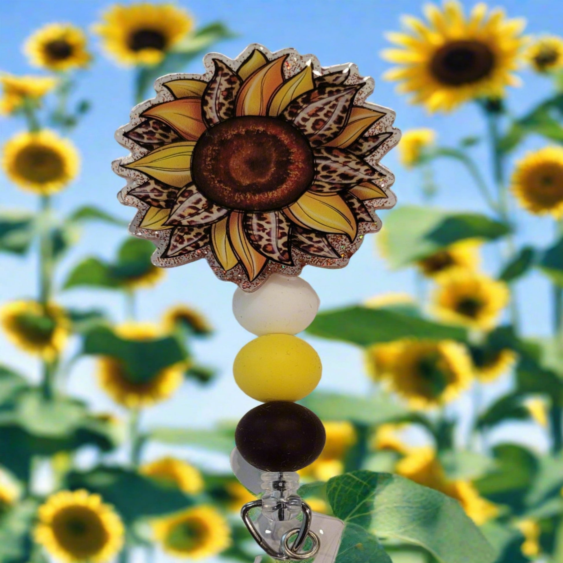 Dare to stand out with the fierce Sunflower Leopard Print Badge Reel. Its vibrant colors and dazzling glitter base will make a statement, enhanced by three coordinating silicone beads for a touch of adventure.
