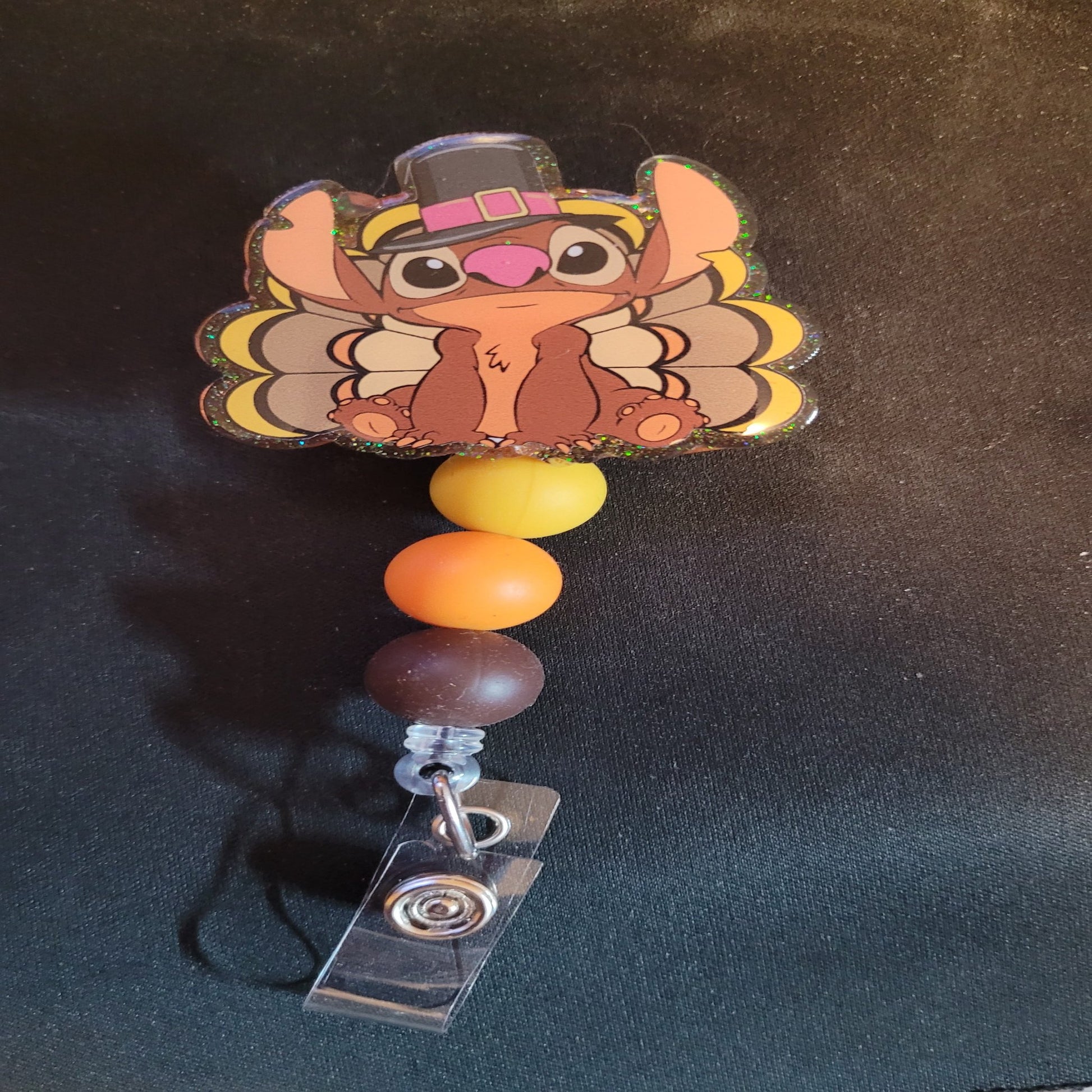 What would Thanksgiving be without a Turkey Stitch. This badge reel has a shiny glitter base and is finished with 3 color coordinated silicone beads.
