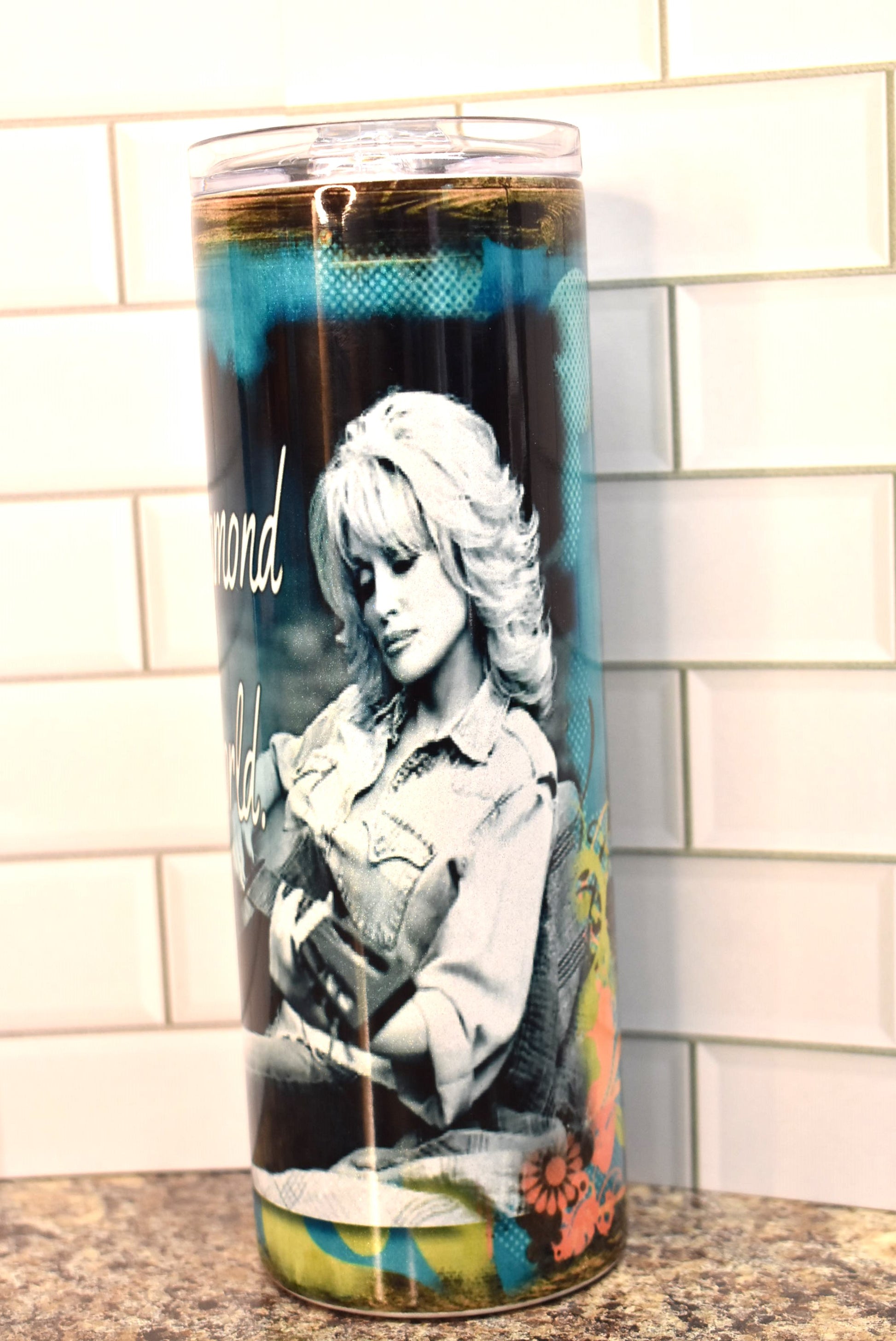 This 20 oz stainless steel Makerflo tumbler features the 1 and only Dolly Parton as she plays a guitar with the phrase....It's hard to be a Diamond in a Rhinestone World .