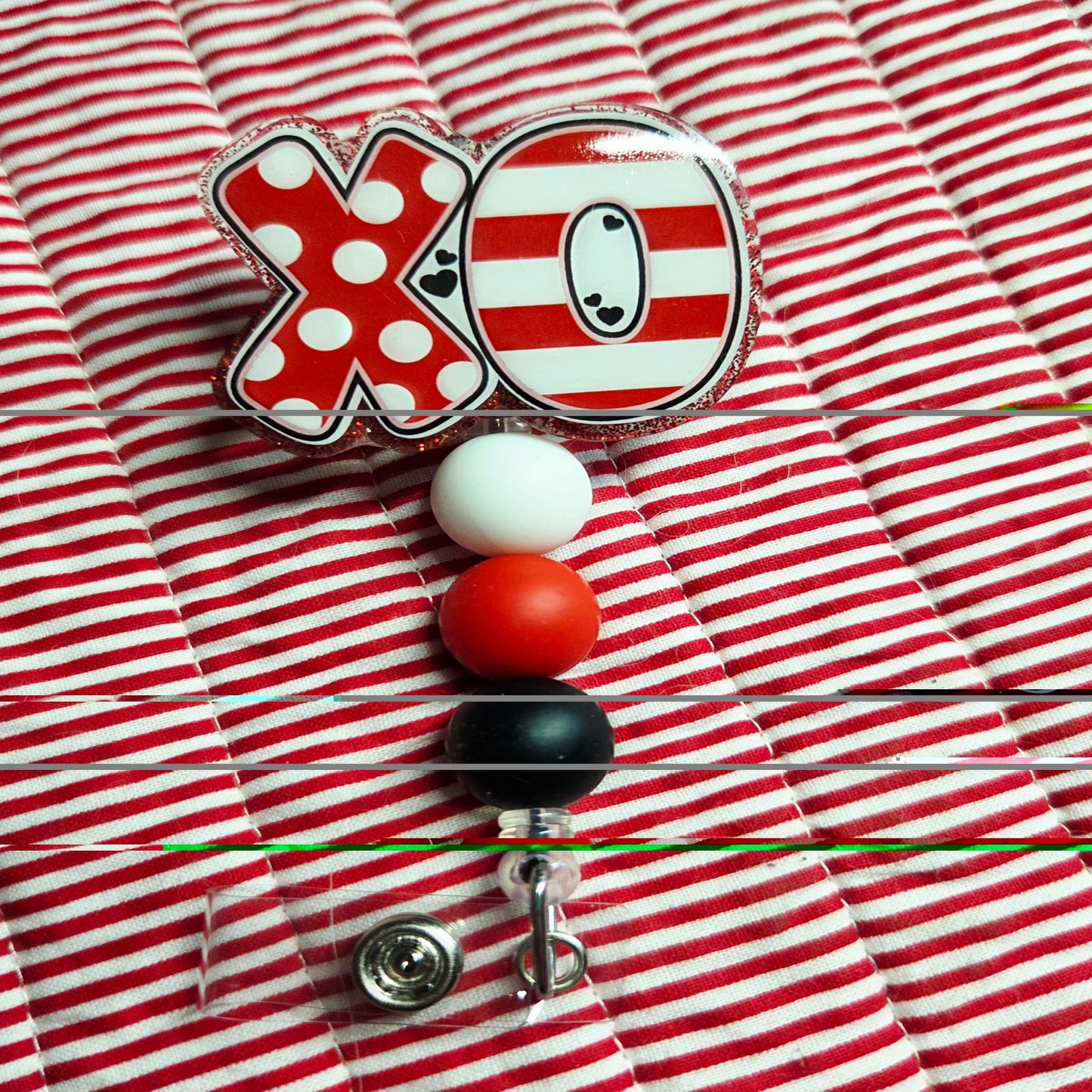 Red and white striped shirt with a badge holder featuring a cartoon character and 'XO' design.