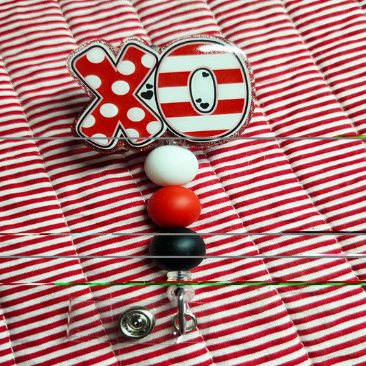 Red and white striped shirt with a badge holder featuring a cartoon character and 'XO' design.