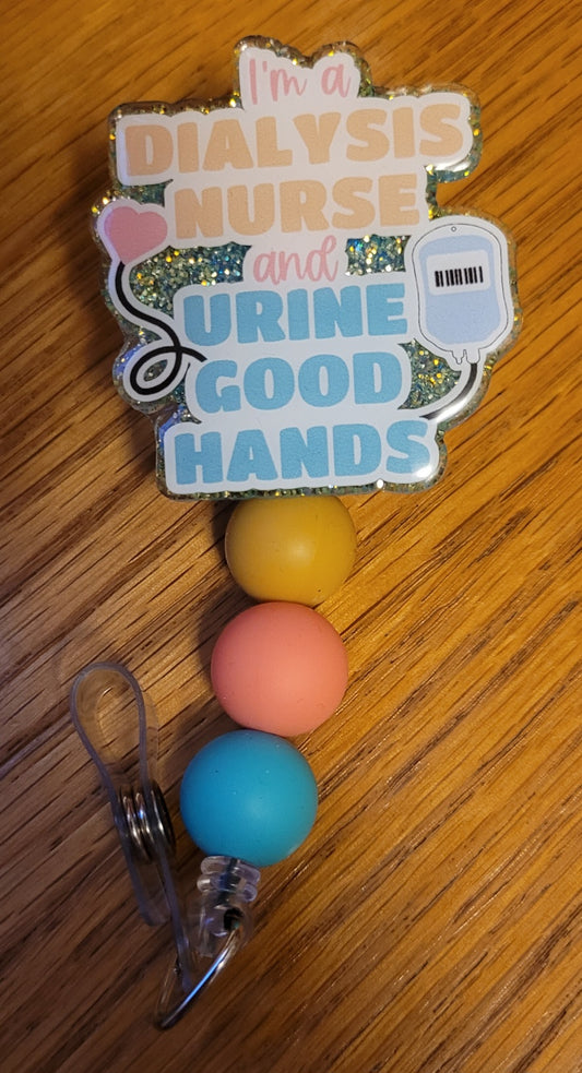 Part of our Medical Badge Reels collection we now have available Dialysis Nurse. Featuring the phrase I'm A Dialysis Nurse And Urine Good Hands on the front with a light blue glitter base on the back adorned with 3 coordinating silicone beads.