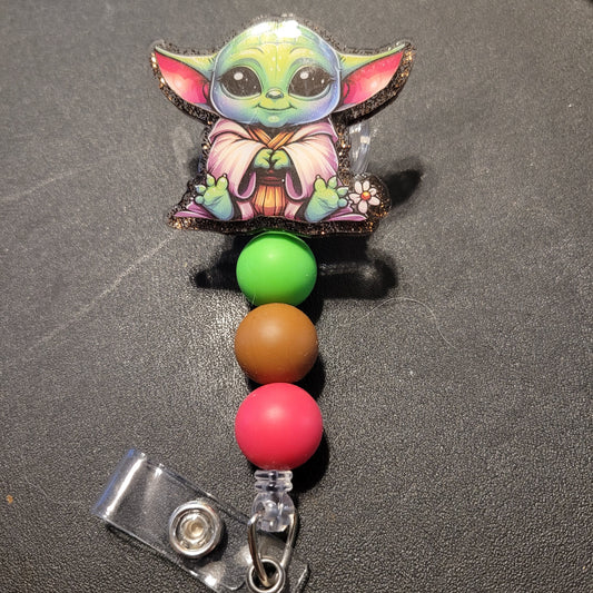 Colorful badge holder with a character design on a dark surface