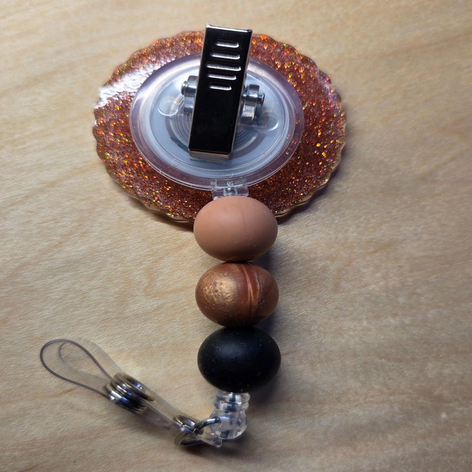 Retractable badge holder with decorative beads on a wooden surface