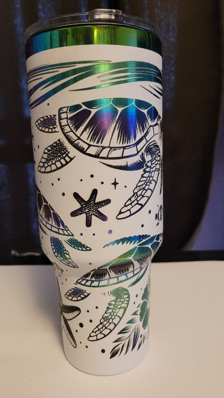 Introducing the latest addition to our collection: the 40 oz Gold Plated Tumbler featuring laser-etched full-wrap from another on a sleek white background. 3 sea turtles swimming around other sea life