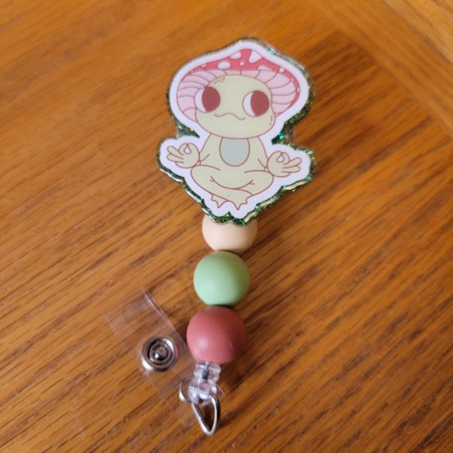 Another new one to our Animal Series... Zen Frog. This cute frog is in a Zen zone in his favorite yoga pose. A dazzling green glitter backing and 3 color-coordinated silicone beads add the perfect finishing touch to this out-of-this-world badge reel.