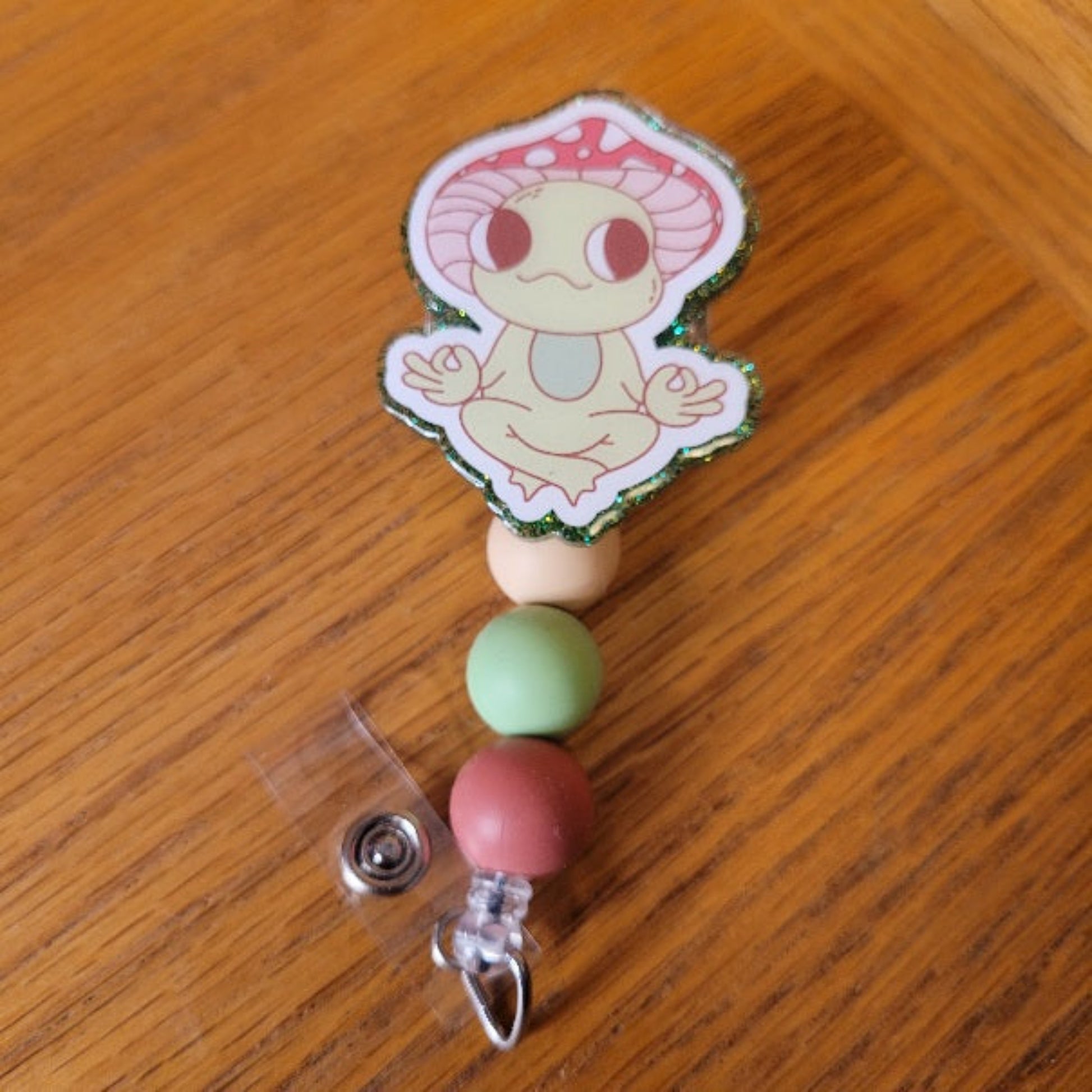 Another new one to our Animal Series... Zen Frog. This cute frog is in a Zen zone in his favorite yoga pose. A dazzling green glitter backing and 3 color-coordinated silicone beads add the perfect finishing touch to this out-of-this-world badge reel.