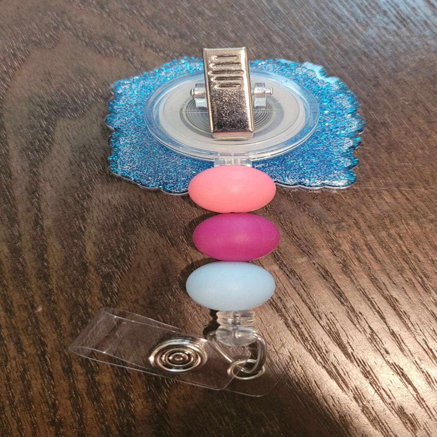 Be Fearless Be Brave is our newest inspirational badge reel. Those words are centered on the front and surrounded by various flowers. Decked With a sparkling blue glitter back and embellished with 3 silicone beads on the cord.