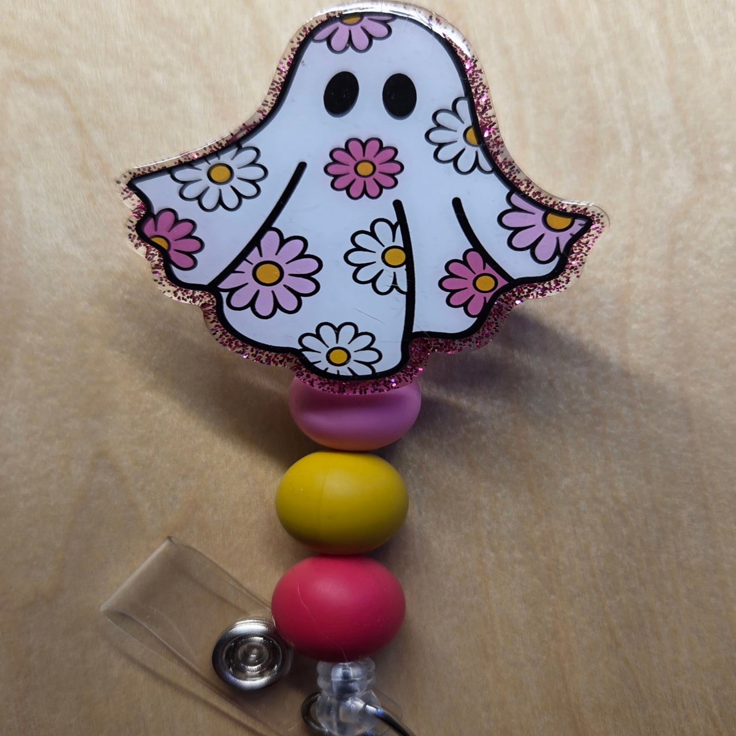 Colorful ghost-shaped badge holder with flowers on a beige background