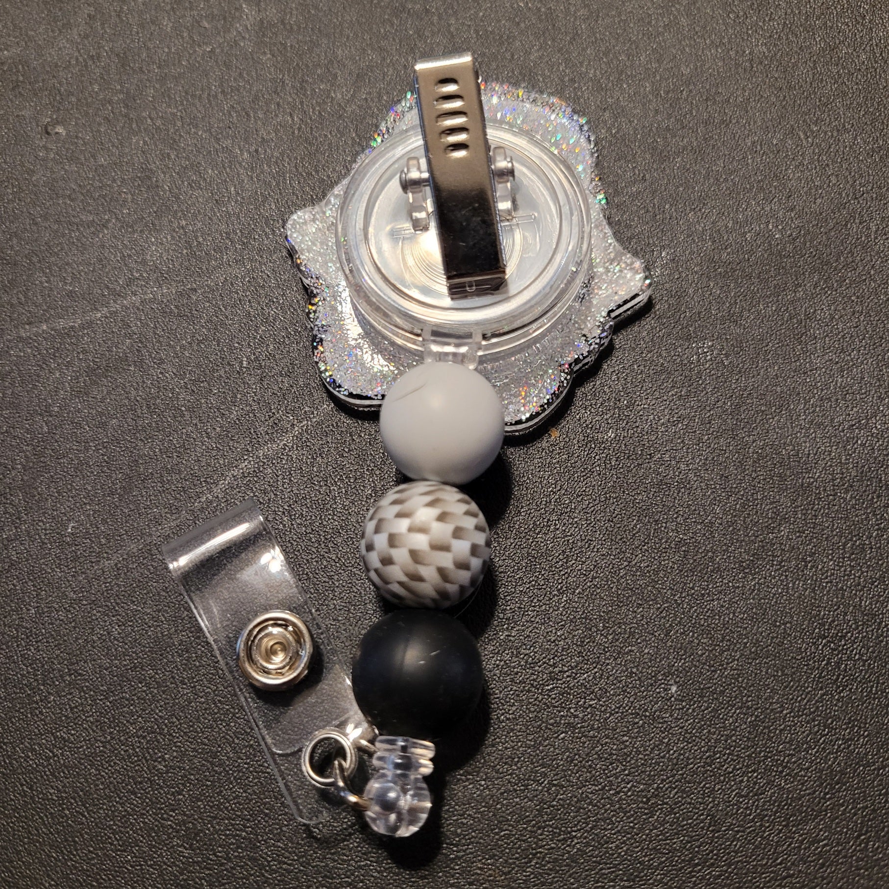 Retractable badge holder with beads on a dark surface
