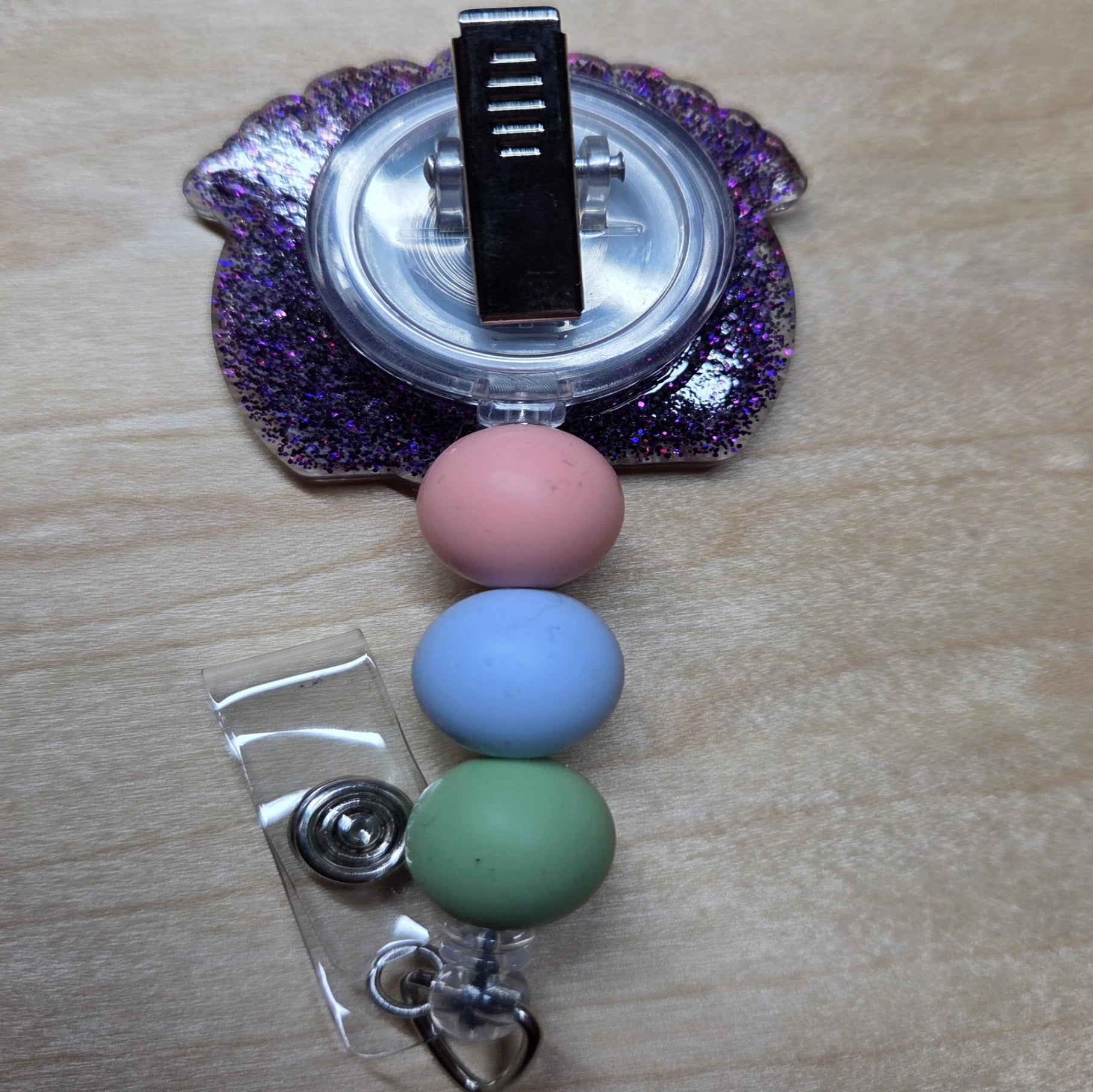 Retractable badge holder with colorful beads on a wooden surface