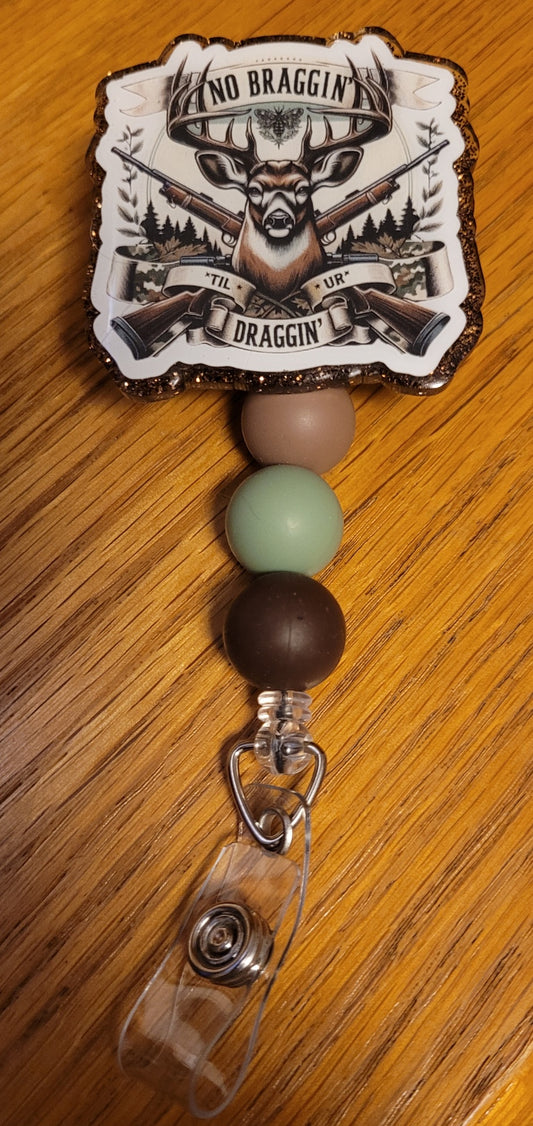 Featuring that dream Big Buck as the main focal point with 2 rifles crossed behind him and a Ribbon with the phrase No Braggin' Til Ur Draggin'. It is finished with a brown glitter base and three carefully chosen silicone beads.