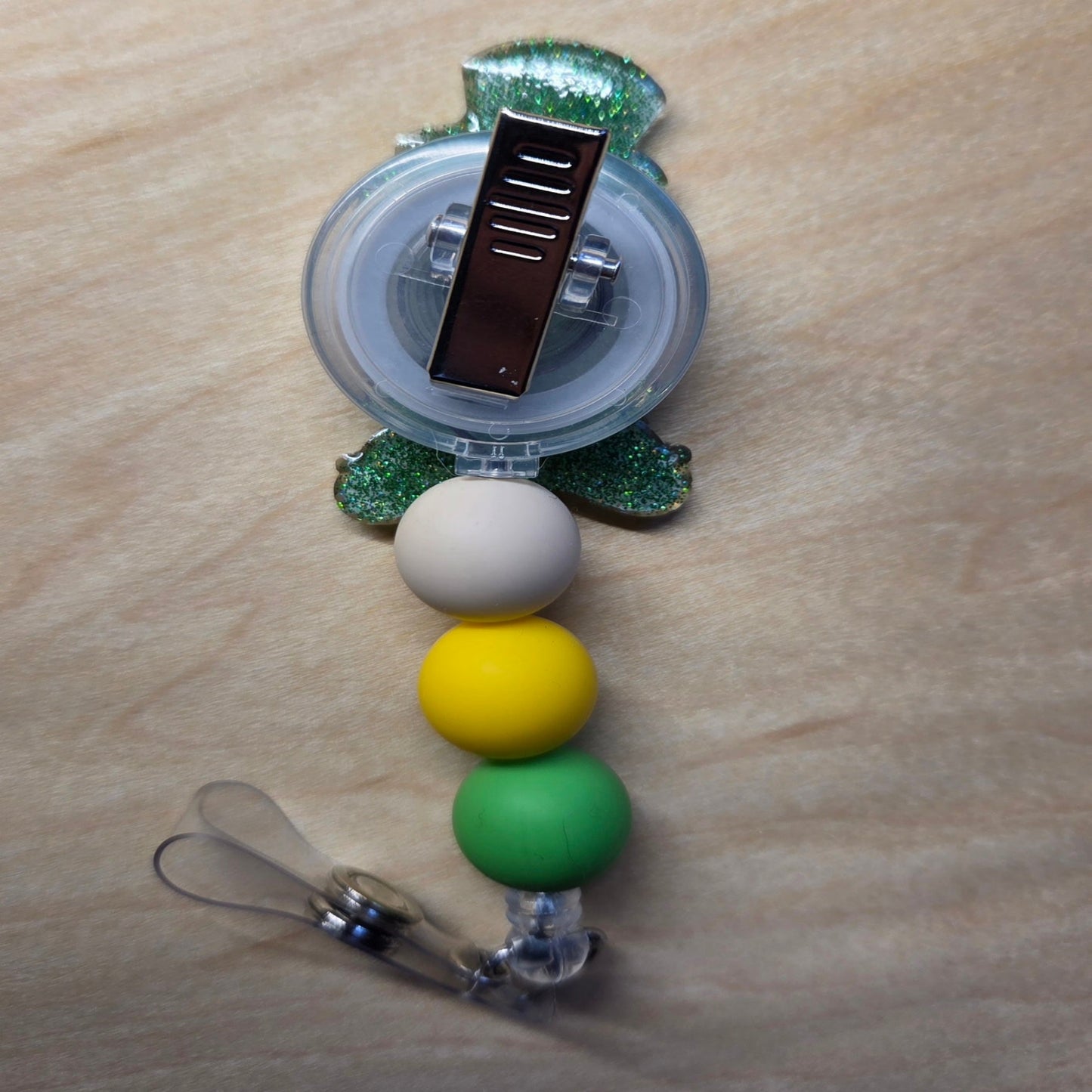 Retractable badge holder with colorful beads on a wooden surface