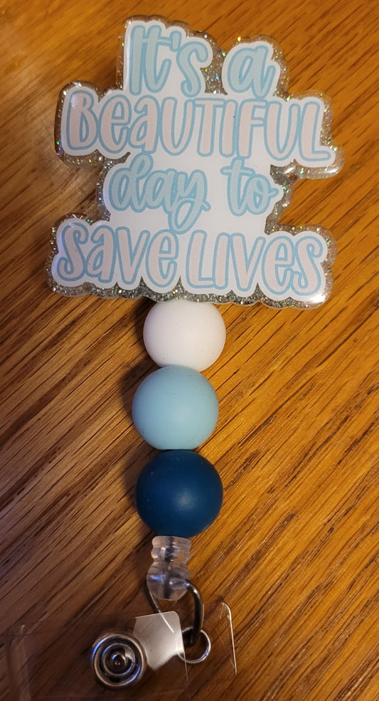 Now Part of our Medical Badge Reels collection, we have available, Save Lives. With the phrase It's A Beautiful Day To Save Lives on the front with a light teal glitter base on the back adorned with 3 coordinating silicone beads. What a great mindset!