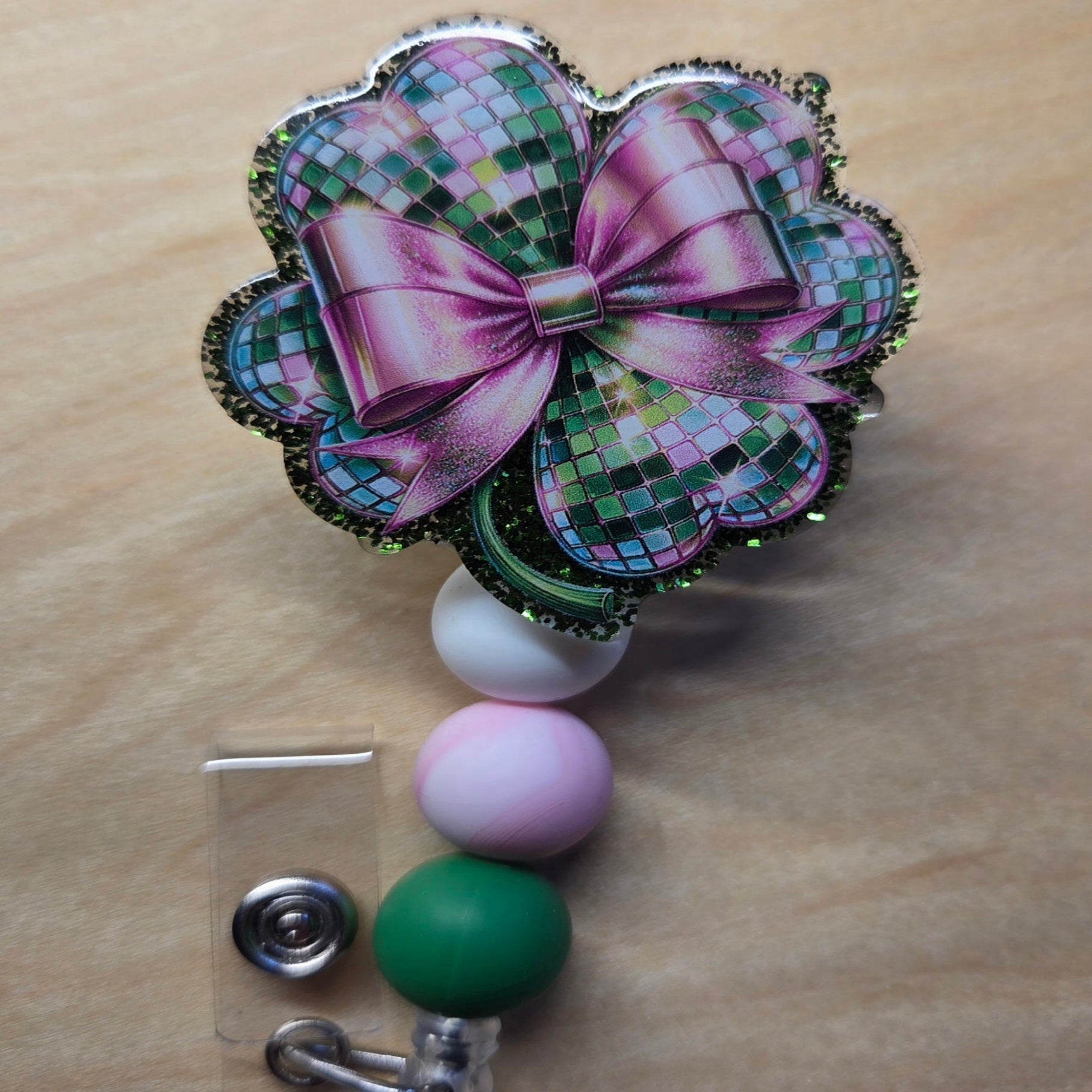 Decorative badge holder with a pink bow and colorful beads on a wooden surface