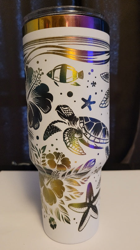 Introducing the latest addition to our collection: the 40 oz Gold Plated Tumbler featuring laser-etched full-wrap from another on a sleek white background. 3 sea turtles swimming around other sea life