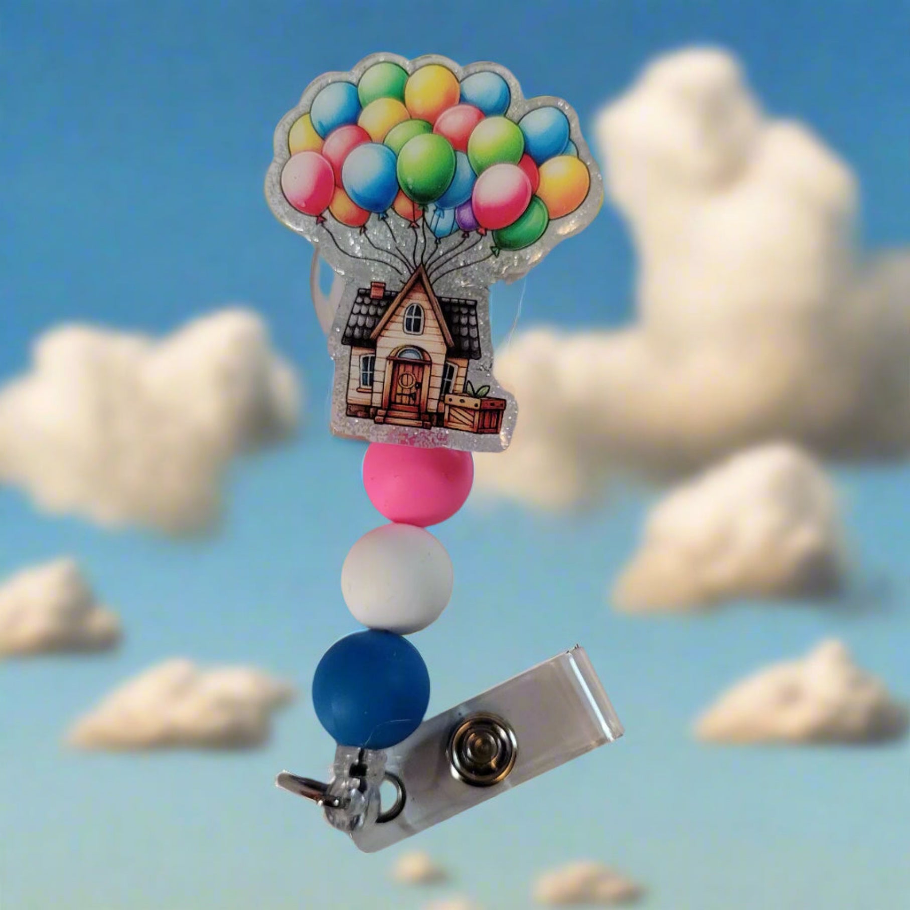 Retractable badge holder with colorful balloons and a house design on a white background
