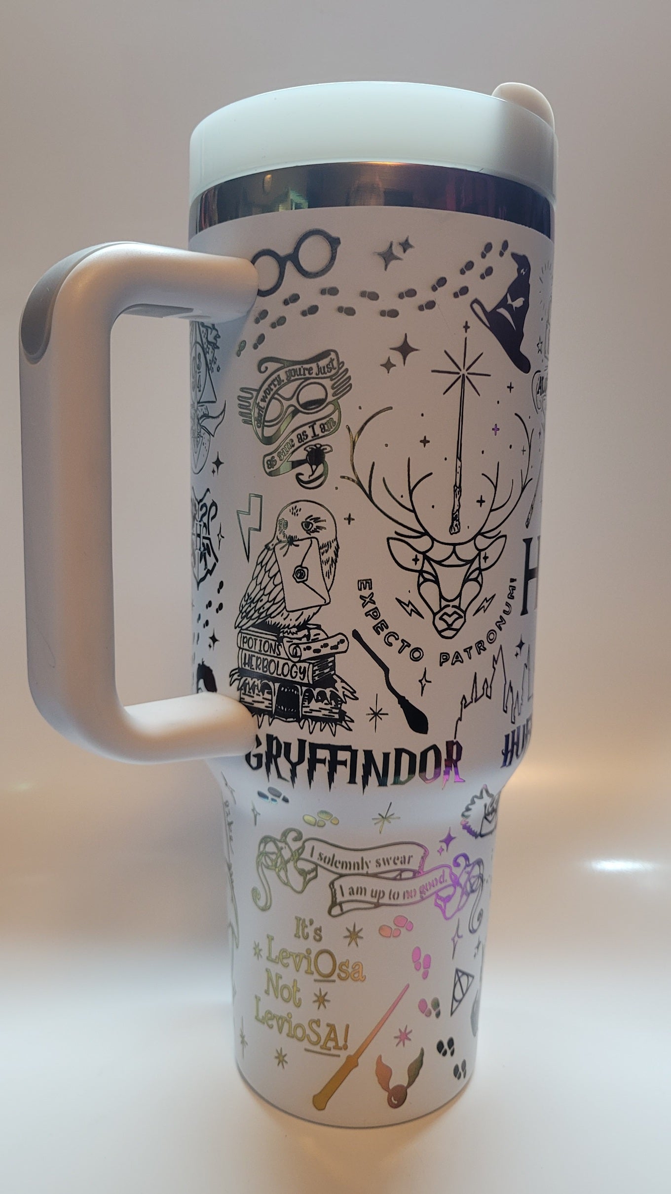 Travel mug with decorative designs and text on a white background