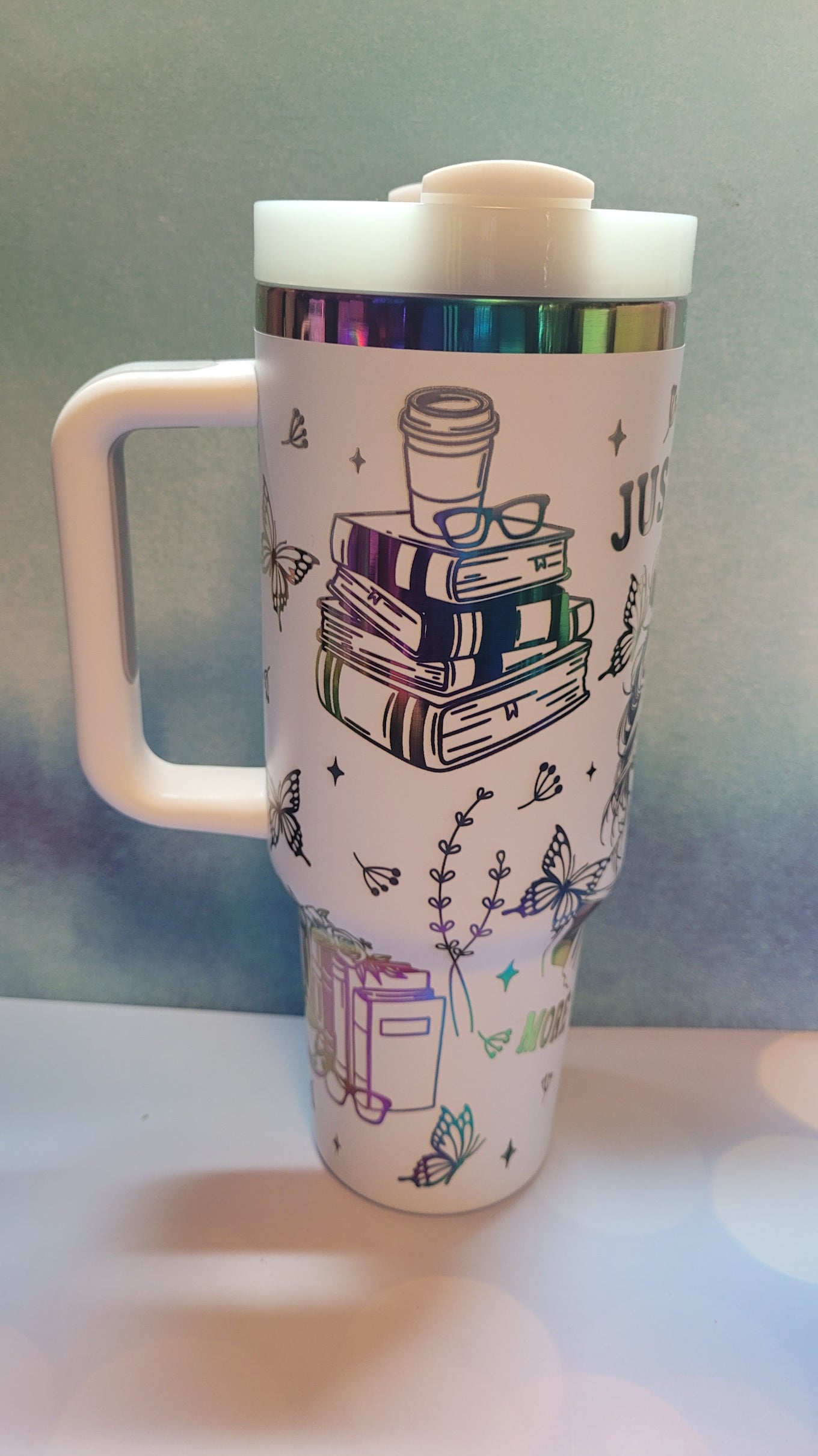 Travel mug with book-themed design on a white surface