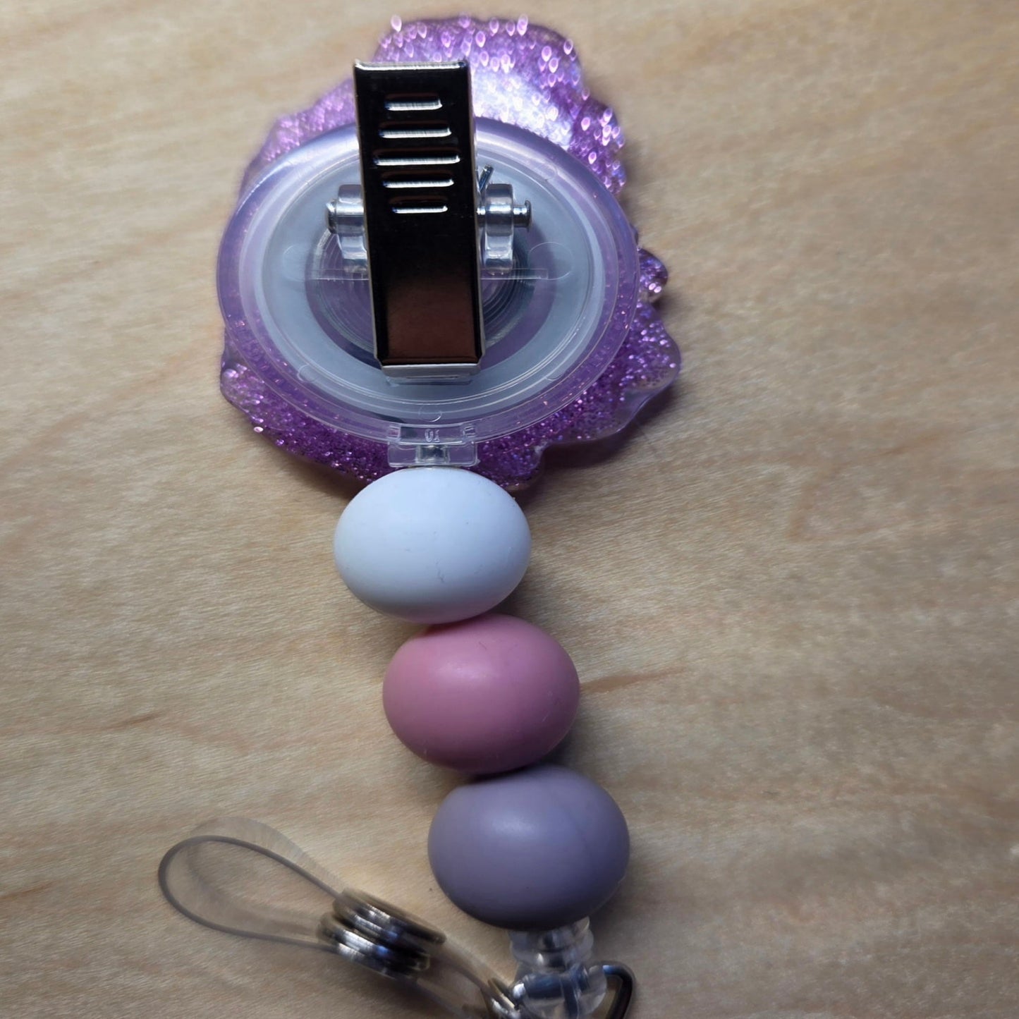 Purple and pink beaded keychain with a clip on a beige surface