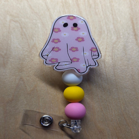Ghost-shaped badge holder with colorful beads on a wooden surface