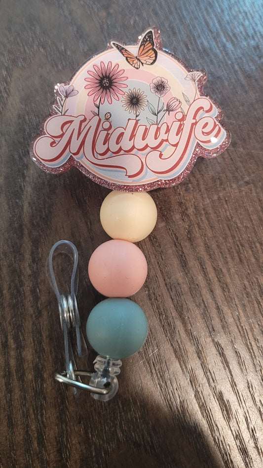 Midwife. For those dedicated in taking care of new moms and their babies. The badge reel features the word Midwife with flowers and a monarch butterfly in the background. The back in a rose gold sparkling glitter and 3 coordinating silicone beads on the cord. 