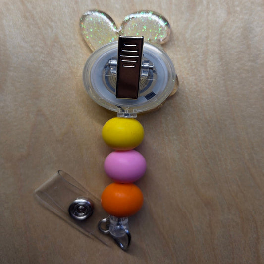 Retractable badge holder with colorful beads and a clear clip on a wooden surface