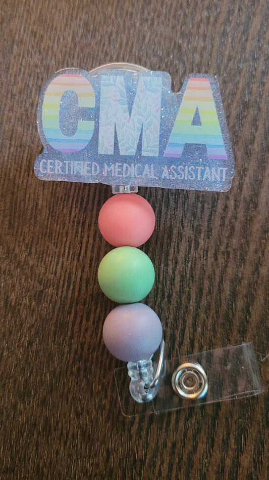 Now Part of our Medical Badge Reels collection, we have available, No not that music awards show, Certified Medical Assistant. That phrase and the letters CMA are on the front with a light blue glitter base on the back adorned with 3 coordinating silicone beads.