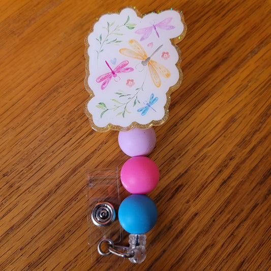 Another new one to our Animal Series... Dragonflies. This badge reel is plain and simple with various dragonflies in various colors and 2 pieces of greenery. A yellow glitter backing and 3 color-coordinated silicone beads add the perfect finishing touch to this badge reel.