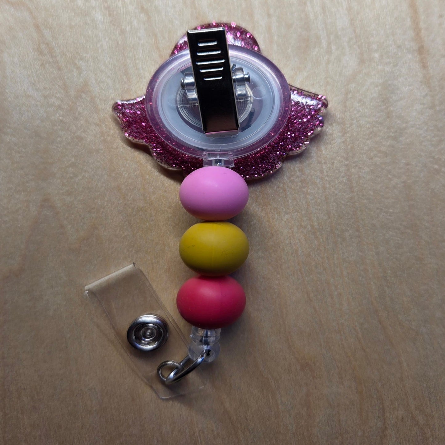 Retractable badge holder with colorful beads on a wooden surface