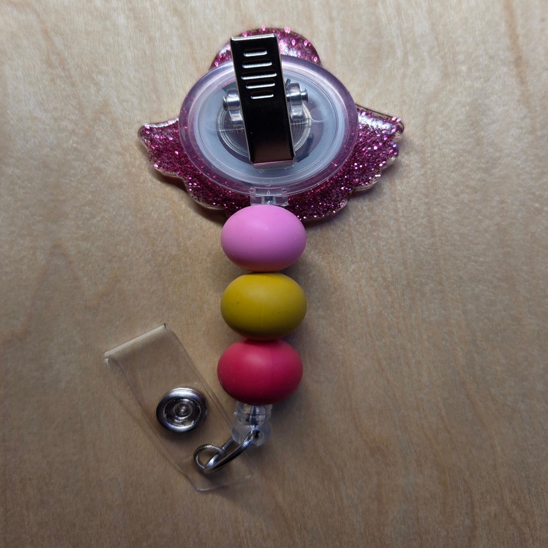 Retractable badge holder with colorful beads on a wooden surface