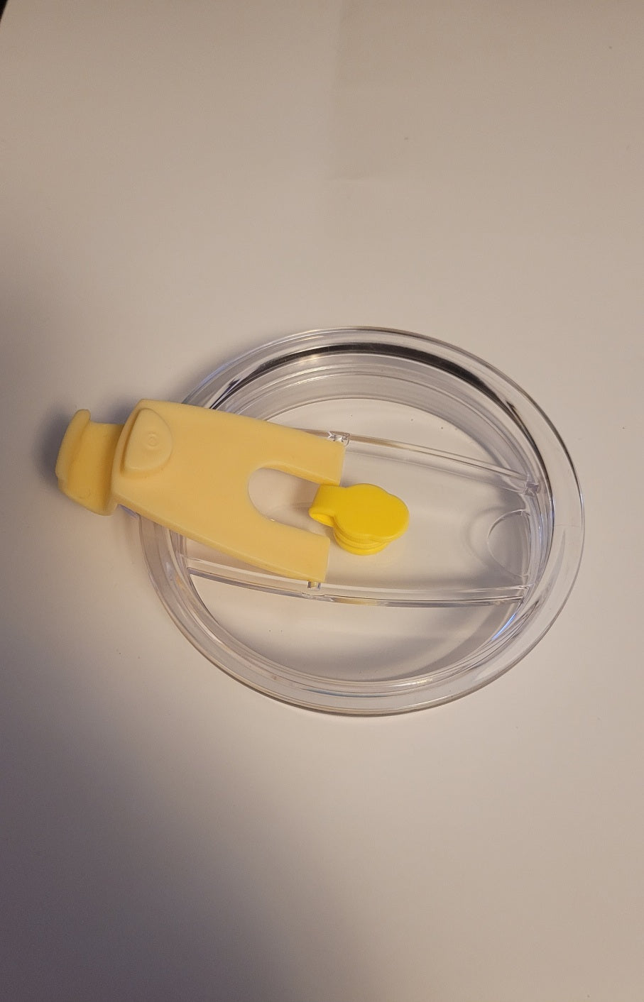 Clear plastic lid with yellow clip on a white background
