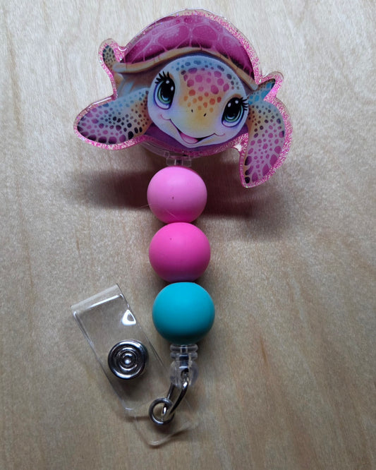 Colorful fish-shaped badge holder with pink and blue beads on a beige background