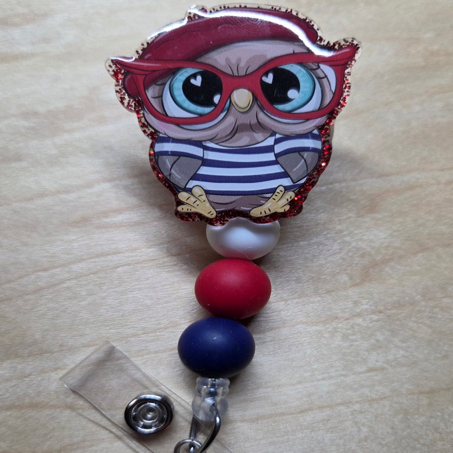 Owl-shaped badge holder with colorful beads on a wooden surface