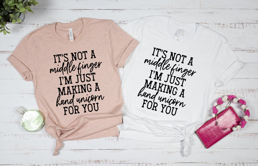 This T-Shirt has a Screen Print Transfer featuring black lettering displaying the phrase: "It's Not A Middle Finger I'm Just Making A Hand Unicorn For You". The fabric is 5.3 oz. 100% preshrunk cotton.  